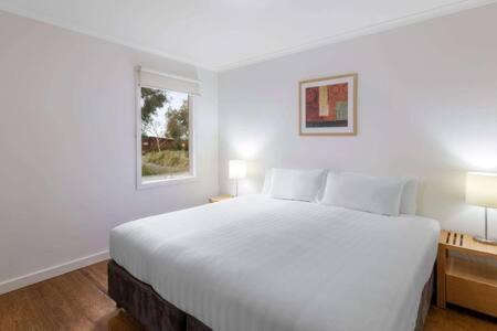 a white bedroom with a large bed and two windows at 241 - Modern Exclusive Resort Villa w Pool Spa & Gym in Cowes