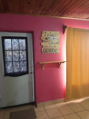 um quarto com uma parede rosa e uma porta com uma placa em Posada Casa del Abuelo. Creel, Chih. em Creel