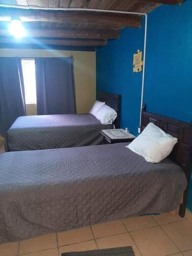 Duas camas num quarto com paredes azuis em Posada Casa del Abuelo. Creel, Chih. em Creel
