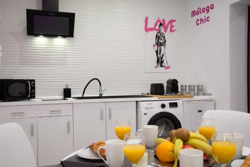 a kitchen with a table with fruit and orange juice at Malaga Chic jacuzzi y playa in Málaga