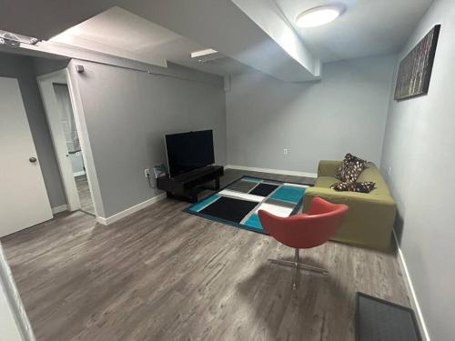 a living room with a couch and a red chair at Cute Highlandpark (Lower B Unit) in Calgary