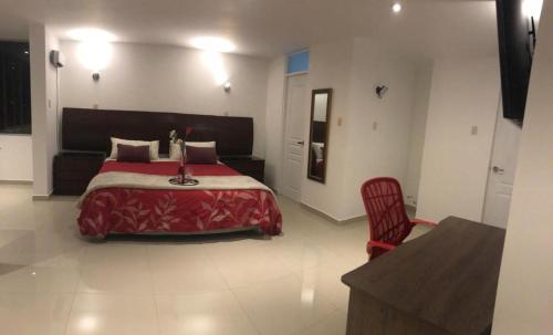 um quarto com uma cama vermelha e uma cadeira vermelha em HOTEL CB CAJAMARCA HUACARIZ em Cajamarca