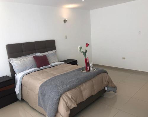 Un dormitorio con una cama con una mesa con flores. en HOTEL CB CAJAMARCA HUACARIZ, en Cajamarca