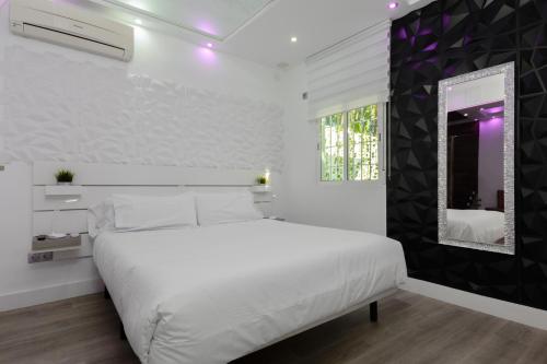 Dormitorio blanco con cama blanca y espejo en Malaga Chic jacuzzi y playa, en Málaga