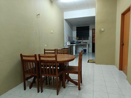 a dining room with a wooden table and chairs at Homestay Tengku Maheran in Jitra