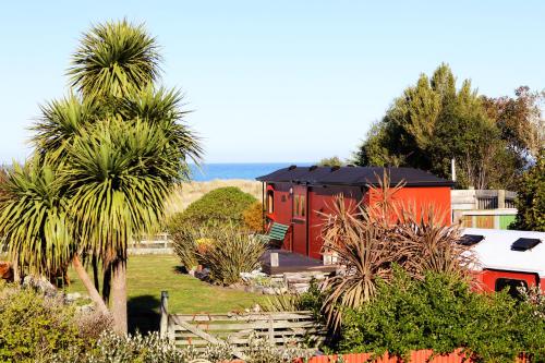 a red and black tiny house with a palm tree at Hapuku Carriages Kaikōura in Kaikoura