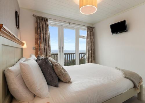 a bedroom with a bed with a large window at Meadow House Holiday Park in Amroth