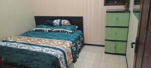 een kleine slaapkamer met een bed en een groene dressoir bij Azalea Homestay in Batu