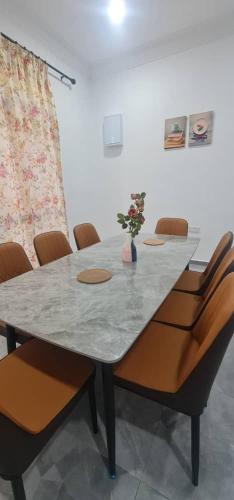 a table with chairs and a vase with flowers on it at Homestay Kuala Dungun in Dungun