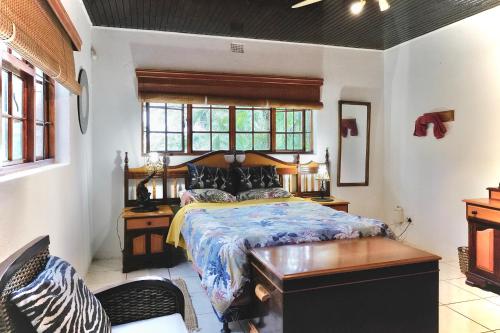 a bedroom with a bed and a desk and window at Leopards Ledge in Nelspruit