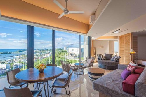 a living room with a couch and a table and chairs at 恩納オーシャンビュースイート in Nakadomari
