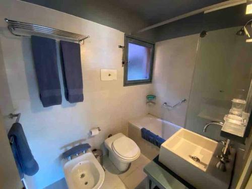 a bathroom with a white toilet and a sink at Apartamento Terrazas de Manantiales frente al mar in Punta del Este