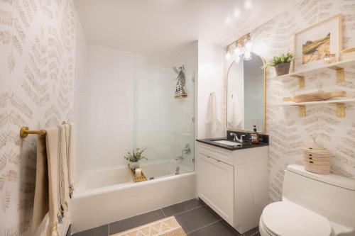 uma casa de banho branca com uma banheira, um WC e um lavatório. em Designer Apt for 6, City Views, near Times Square! em Nova York