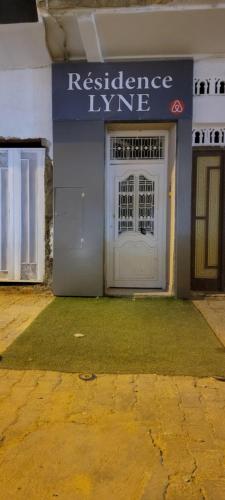 ein Gebäude mit einer weißen Tür und einem Schild darauf in der Unterkunft Residence Lyne in Kairouan