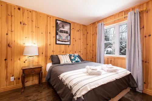 a bedroom with wooden walls and a bed with towels on it at Chalet le Boréal: Massif, spa et montagnes in Petite-Rivière-Saint-François