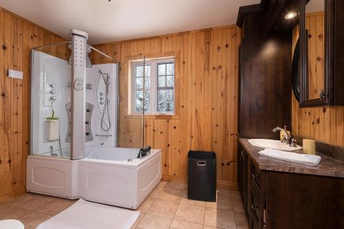 a bathroom with a large tub and two sinks at Chalet le Boréal: Massif, spa et montagnes in Petite-Rivière-Saint-François