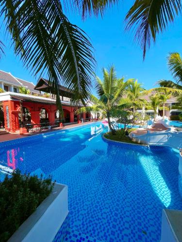 a swimming pool with palm trees and a resort at Manyo Hotel and Resort in Luang Prabang