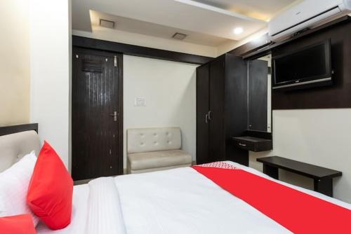 a bedroom with a bed and a television and a chair at Hotel Trishla in Bhopal