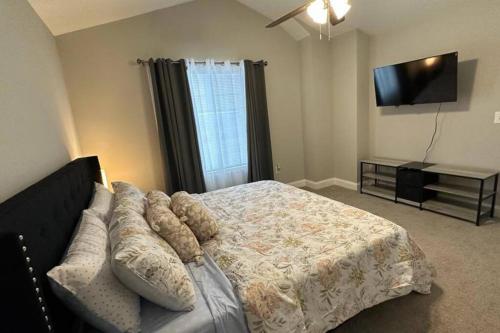 a bedroom with a bed and a couch and a flat screen tv at Spacious 3-Bedroom Modern Home Near CLT Motor Speedway in Concord
