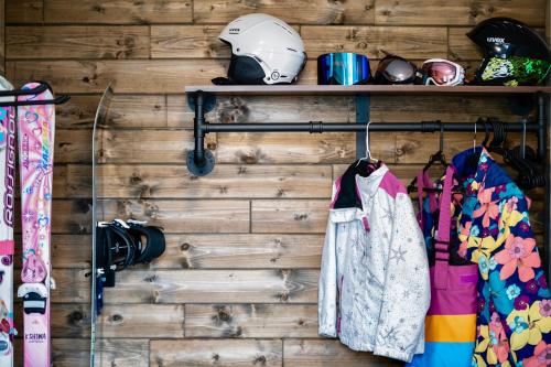 a room with a wooden wall with a helmet and clothes at FuranoSky - White in Furano