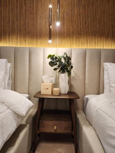 a table with a plant on it next to two beds at Sheema Lodge in Hatta