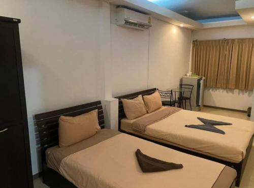 a room with two beds and a table with a table at jomtien seaside guesthouse in Jomtien Beach
