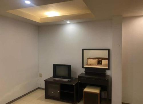Habitación con TV y espejo en una mesa. en jomtien seaside guesthouse, en Jomtien Beach