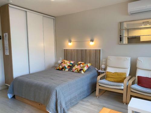 une chambre avec un lit et deux chaises dans l'établissement Studio Confort en Face des Thermes - Loggia, Clim, Parking - Balaruc-les-Bains - FR-1-553-243, à Balaruc-les-Bains