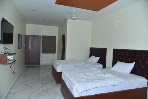 a bedroom with two beds and a flat screen tv at The Paradise Guest Inn in Nellore