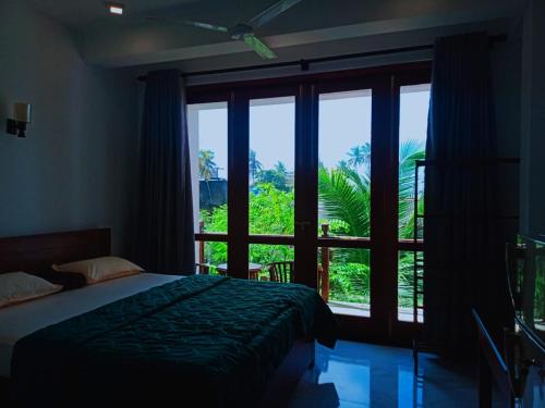 a bedroom with a bed and a large window at BLUE WHALES HOTEL in Hikkaduwa
