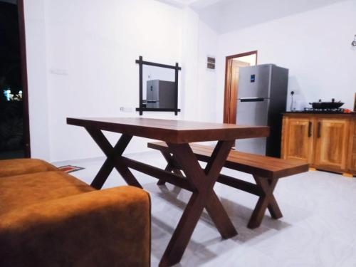a wooden table in a kitchen with a refrigerator at BLUE WHALES HOTEL in Hikkaduwa