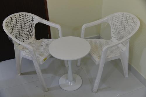 two white chairs and a white table and stool at The Paradise Guest Inn in Nellore