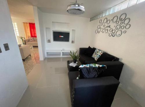 a living room with a black couch and a tv at Casa Blanca in Santo Domingo