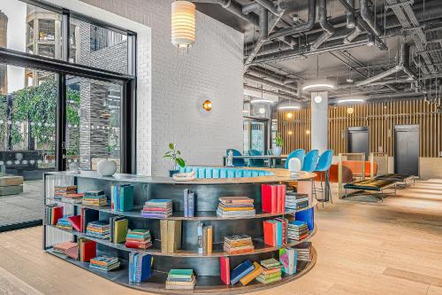 a library with shelves filled with books and blue chairs at Modern King's Cross Apartments in London