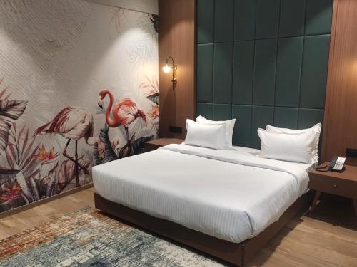 a bedroom with a bed and a painting of flamingos at park royal hotel in Dwarka