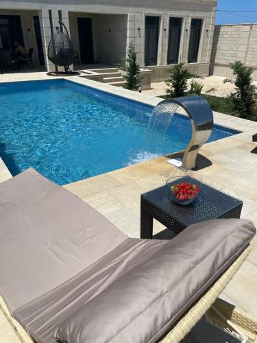 una piscina con un sofá y una fuente de agua en Дом у моря Мардакане en Mardakan