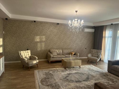 a living room with a couch and chairs and a chandelier at Дом у моря Мардакане in Mardakan