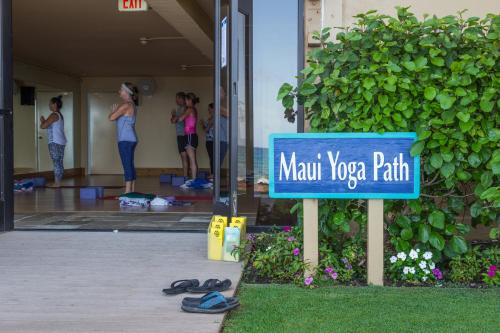 a sign in front of a building with people doing yoga at Mana Kai Maui - Official Onsite Rental Company in Wailea