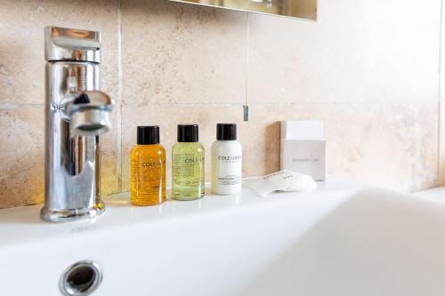 a bathroom counter with three bottles of soap and a sink at Gilmoreton House in Leicester