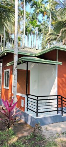 una casa con una panchina davanti di Areca Adventures Family Cottage a Kushalnagar