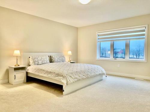 ein weißes Schlafzimmer mit einem Bett und einem Fenster in der Unterkunft Spacious 4BR Home near Hamilton Airport in Caledonia