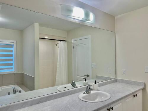 ein Badezimmer mit zwei Waschbecken und einem großen Spiegel in der Unterkunft Spacious 4BR Home near Hamilton Airport in Caledonia