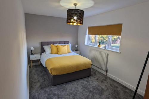 ein Schlafzimmer mit einem Bett mit gelben Kissen und einem Fenster in der Unterkunft Gilliver House in Newbold Verdon