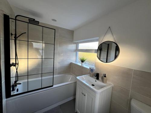 a bathroom with a tub and a sink and a mirror at Gilliver House in Newbold Verdon