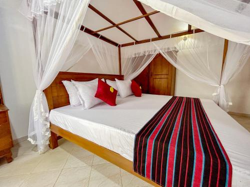 マータラにあるDill Villa Matara Walpola - Cozy 3bedroom 2Bathroom -Entire Floorのベッドルーム1室(天蓋付きベッド1台、赤と白の枕付)