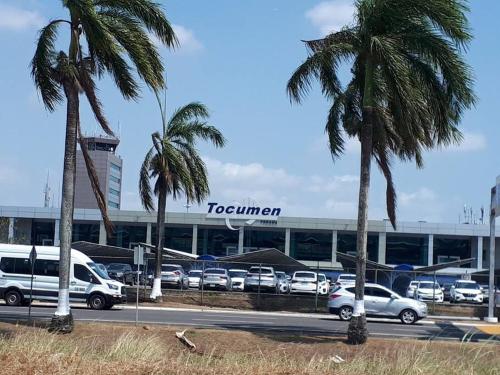 a parking lot with palm trees in front of a terminal at The best place to rest near Tocumen Airport in Panama City
