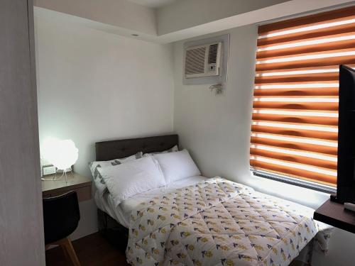 a small bedroom with a bed and a window at A Home with a view, 1 Bdrm with balcony and Netflix Access in Manila