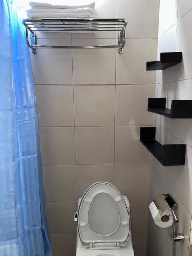 a bathroom with a toilet with a blue shower curtain at A Home with a view, 1 Bdrm with balcony and Netflix Access in Manila