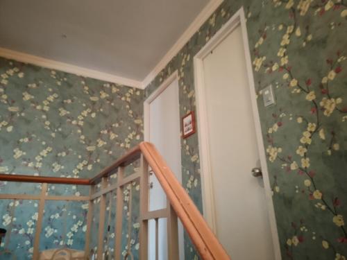 a room with a staircase with floral wallpaper at Camellia Fionza in Apalit