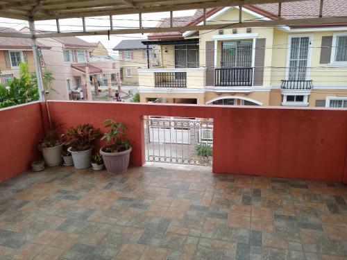 an outdoor patio with a red fence and plants at Camellia Fionza in Apalit